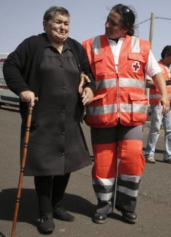 Un miembro de Cruz Roja camina con una anciana.