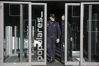 Dos agentes de la Policía Nacional salen de la sede central del Partido Popular, en Madrid. (Foto: JAVIER LIZÓN)