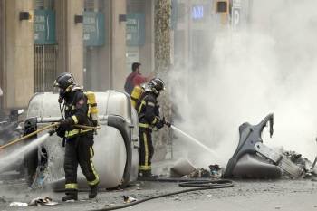 Dos bomberos apagan contenedores en los disturbios de Burgos.