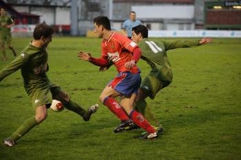  (Foto: El ourensanista Borja Valle intenta escaparse de dos futbolistas del filial rojiblanco. )