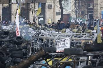 Decenas de manifestantes permanecen de pie frente a una barricada en Kiev. (Foto: SERGEY DOLZHENKO)