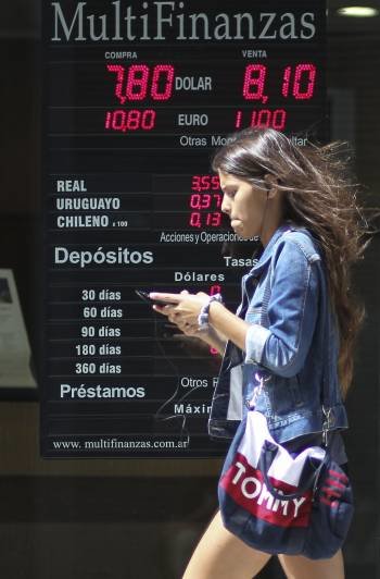 Una joven argentina pasa ante un cartel con el cambio de divisas en Buenos Aires. (Foto: DAVID FERNÁNDEZ.)