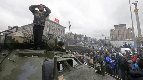Un niño permanece de pie sobe un vehículo militar en la Plaza de la Independencia en Kiev (HOHEM GOUVEIA)