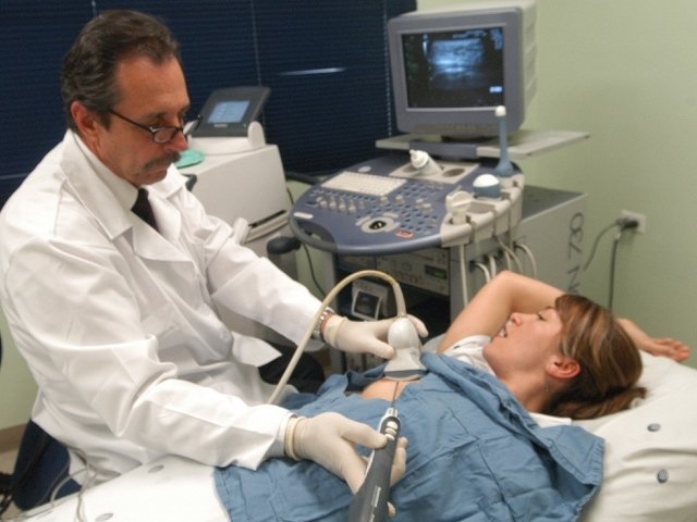 Un médico realiza una exploración a una mujer joven en el pecho.
