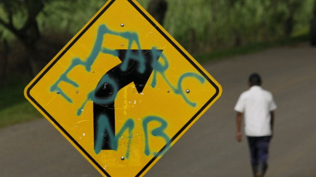 Un hombre pasa junto a una señal de tránsito marcada con mensajes alusivos a las FARC