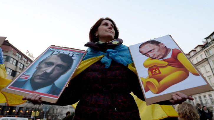 Una mujer lleva dos carteles anti-Putin durante una protesta