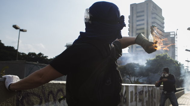 Un manifestante lanza un objeto ardiendo en una protesta en Caracas