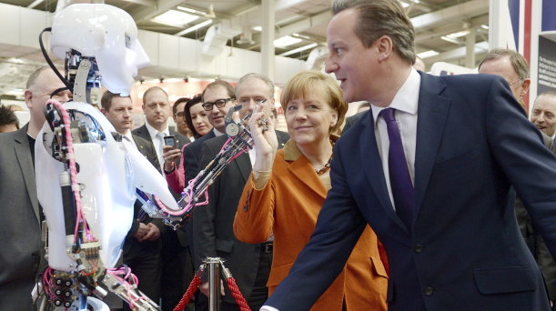 La canciller alemana, Angela Merke y el primer ministro británico, David Cameron, observando un robot en la feria CeBIT 