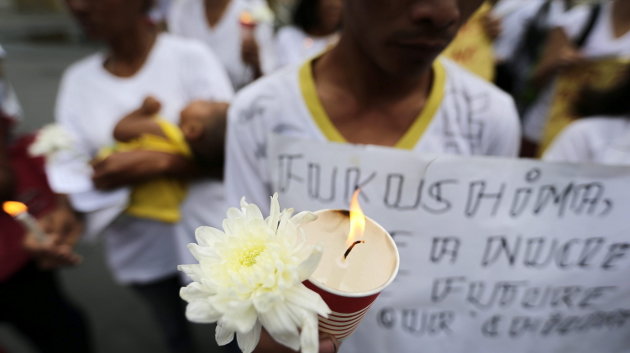 Filipinos encienden velas mientras rezan con motivo del tercer aniversario del terremoto y posterior tsunami 