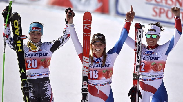 La suiza Laura Gut celebra su victoria en el descenso femenino junto a la ganadora de la segunda posición y la del tercer lugar