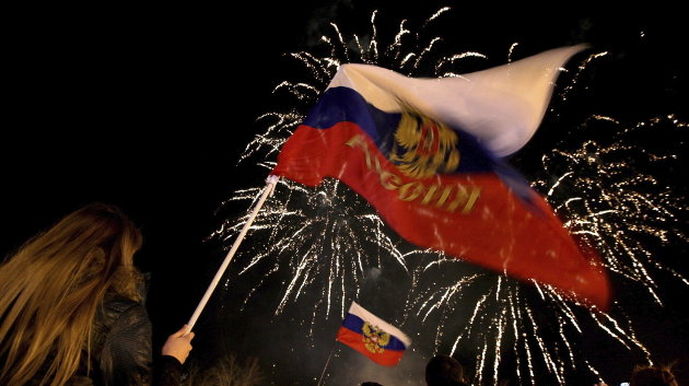 Unas personas sostienen mientras banderas de Rusia durante la celebración por los resultados del referéndum