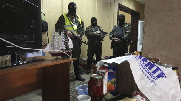 Un grupo de milicianos prorrusos, armados con un rifles automáticos, permanecen en el interior del edificio de la Fiscalía