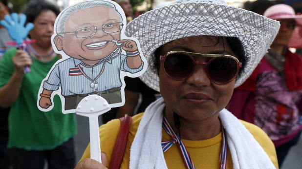 Una manifestantes antigubernamentales sostiene una caricatura del líder opositor Suthep Thaugsuban durante una marcha protesta
