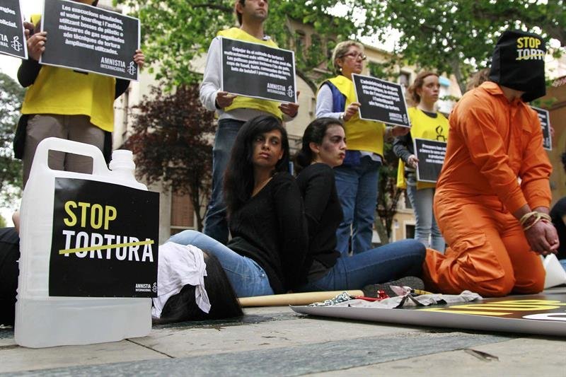 Miembros de Amnistía Internacional durante el acto que han organizado en la Rambla de Barcelona con la escenificación de cuatro víctimas de la tortura, para presentar la campaña &#34;Stop Tortura&#34;
