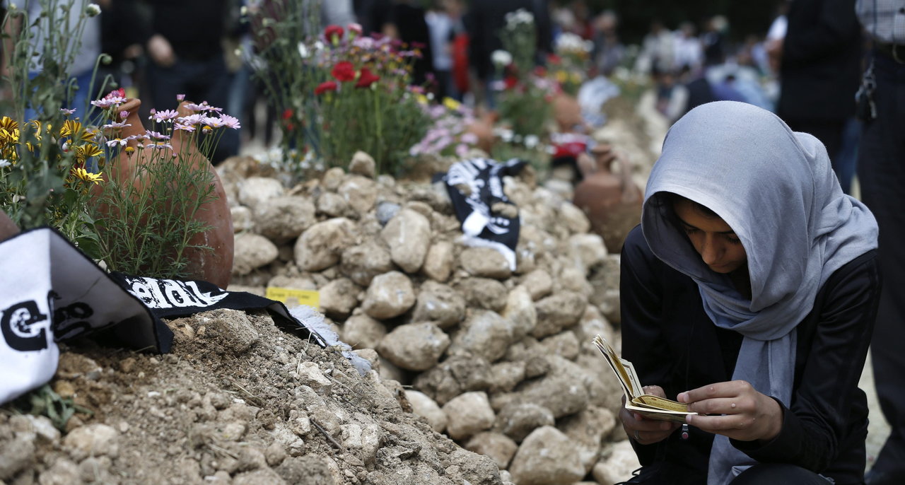Una mujer reza junto a las tumbas de los mineros que perdieron la vida en la explosión