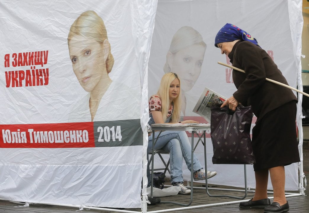 Una mujer de avanzada edad recoge propaganda electoral en un puesto