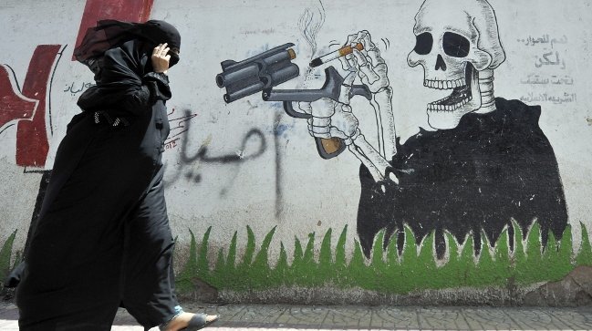 Una mujer pasa ante un mural contra el tabaco en una calle de Saná, capital de Yemen (YAHYA ARHAB)