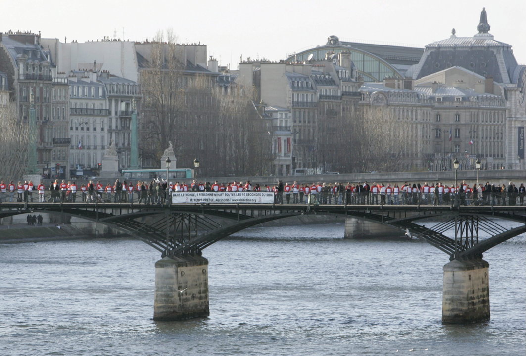 Fotografía de archivo del pasado 1 de diciembre del 2007 que muestra a varios miembros de la asociación Sidaction, que luchan contra el sida, vestidos con camisetas rojas y blancas, haciendo una cadena humana a lo largo del puente Pont des Arts