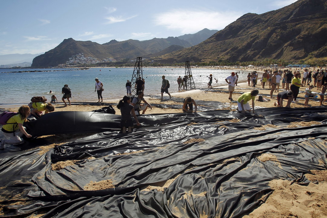 Activistas de la organización ecologista Greenpeace han escenificado hoy los efectos que tendría una marea negra en las playas canarias