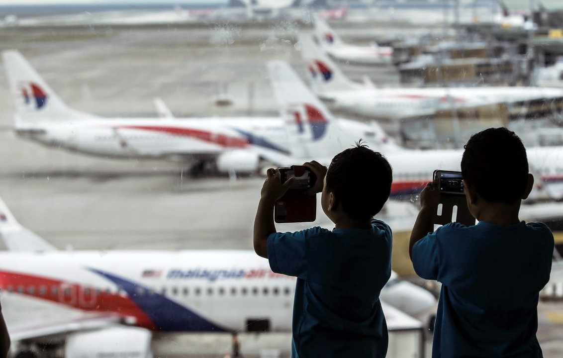 Dos niños toman fotografías de los aviones de Malaysia Airlines en el aeropuerto de Kuala Lumpur en Sepang