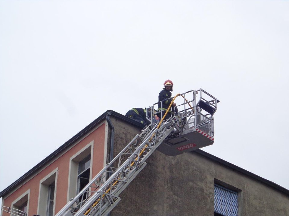 Dos bomberos sobre el tejado del edificio siniestrado.