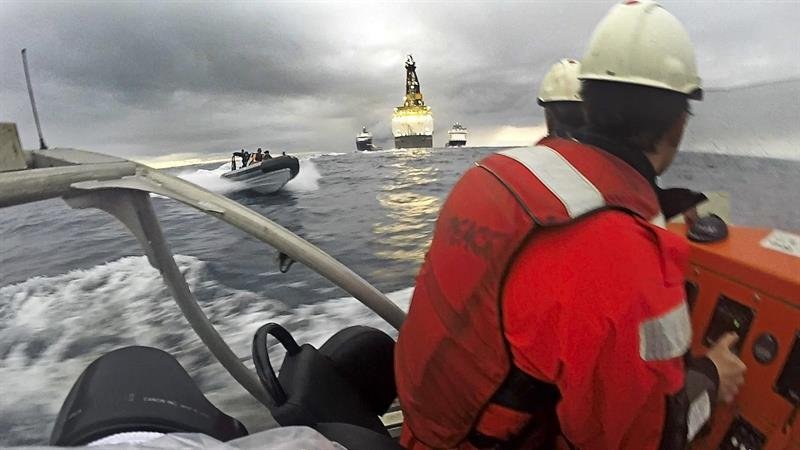 Fotografía facilitada por Greenpeace de dos activistas en una de sus lanchas y otra de la Armada española acercándose por la izquierda