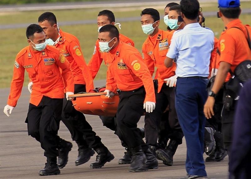 Miembros de los servicios de emergencia transportan el cadáver de una de las víctimas recuperadas del avión de AirAsia siniestrado a su llegada al aeropuerto en Pangkalan Bun