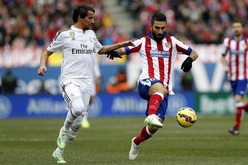  El defensa portugués del Real Madrid, Fabio Coentrao (i), pelea un balón con el centrocampista turco del Atlético de Madrid Arda Turan