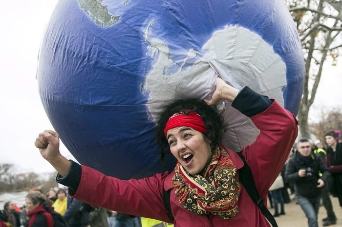 ETI6479. Paris (France), 12/12/2015.- A woman carries an inflatable earth as thousands of people demonstrate in front of the Eiffel Tower for climate change in Paris, France, 12 December 2015. The 21st Conference of the Parties (COP21) is held in Paris from 30 November to 11 December aimed at reaching an international agreement to limit greenhouse gas emissions and curtail climate change. (Francia) EFE/EPA/ETIENNE LAURENT