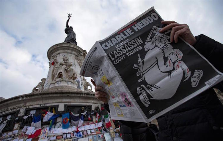 Un parisino lee el número especial de Charlie Hebdo frente a un altar civil en memoria de los atentados que sufrió la ciudad en 2015.