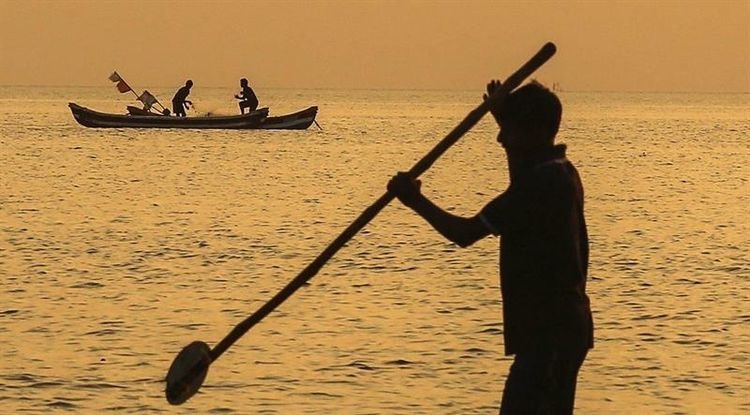 Varios pescadores indios trabajan a la puesta del sol en la costa del mar de Omán en Bombay (India)
