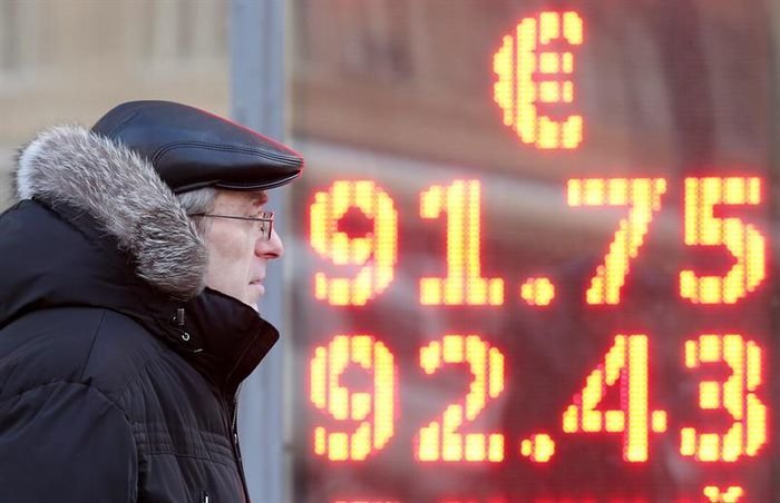 Un hombre camina junto a una oficina de cambio de moneda donde se muestra información del valor del rublo en Moscú (Rusia).