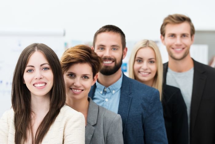 Conceptual image of team leadership with a group of professional successful young business men and women standing in a line headed by two attractive smiling businesswomen