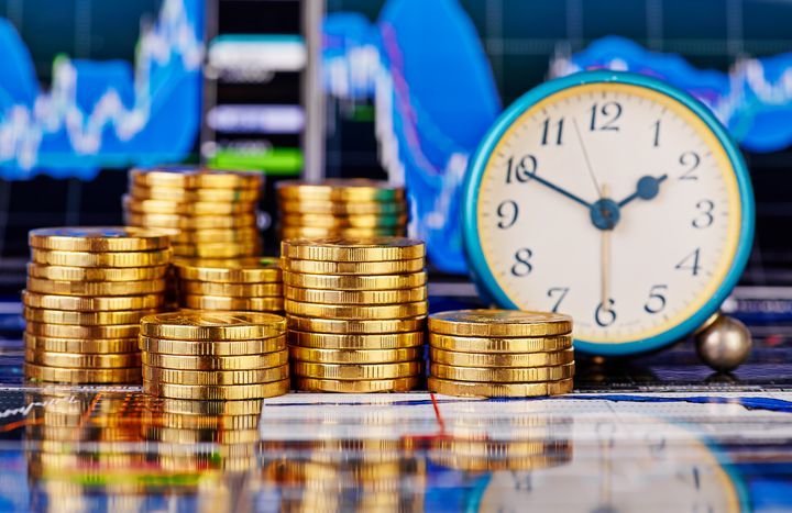 Stacks of golden coins, clock and the financial chart as background. Selective focus