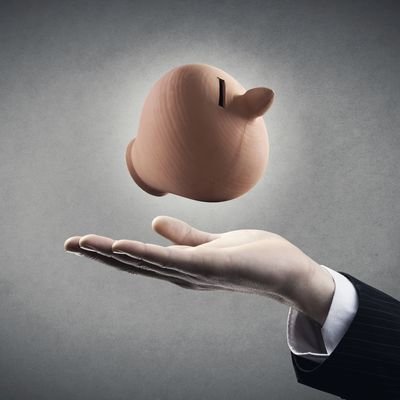 Businessman hand showing a clay coin bank on gray background.