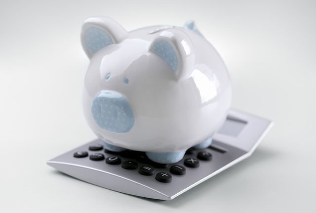 Piggy bank sitting on top of a calculator concept for calculating finance, accounting and tax