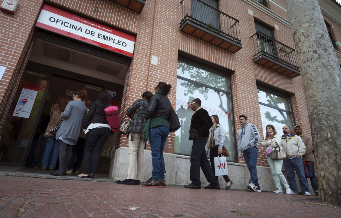 Un grupo de personas esperan en una cola para entrar a una oficina de empleo.