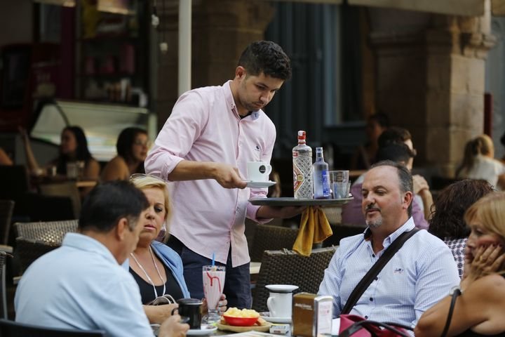 Un camarero atiende a clientes de una terraza de la ciudad.