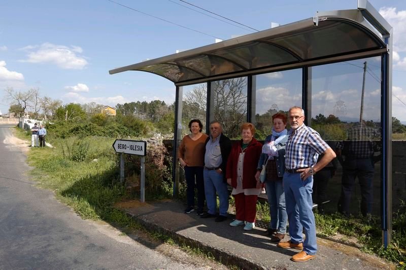 Un grupo de vecinos de Beiro posa en la marquesina, y otro en el lugar en el que efectúa la parada el autobús, a 20 metros (XESÚS FARIÑAS).