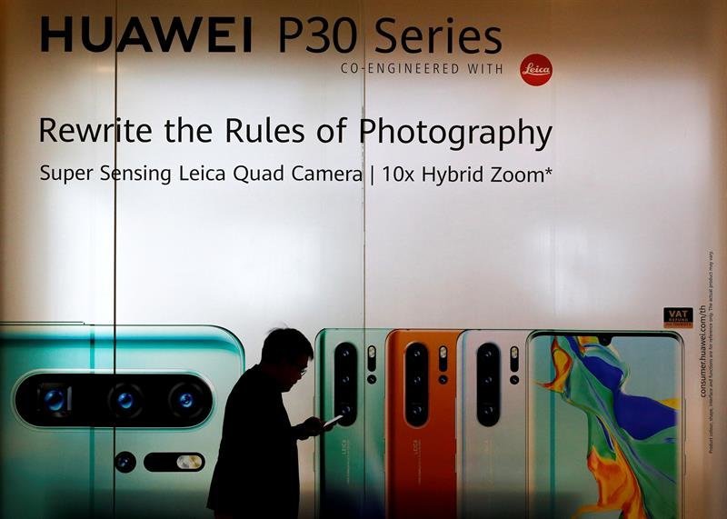 Un hombre pasa por delante de un anuncio de Huawei.