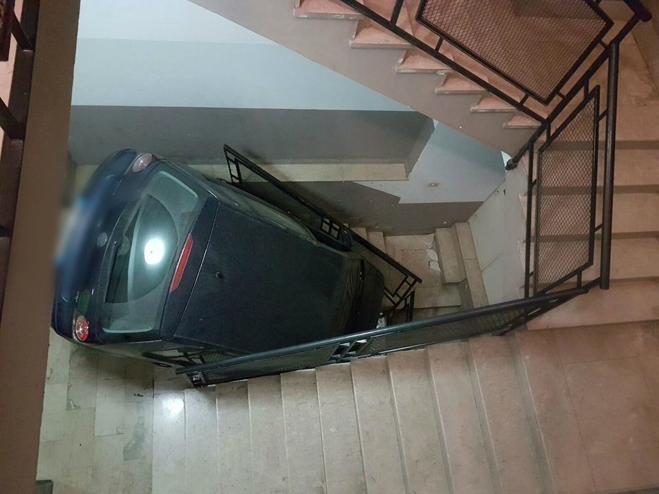 Un coche, encajado en el hueco de las escaleras.