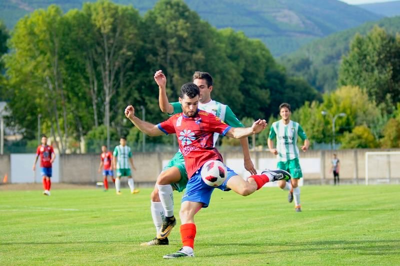 Iker Revuelta se dispone a golpear el balón ante la presión de un jugador del Somozas en Calabagueiros (MARTIÑO PINAL).