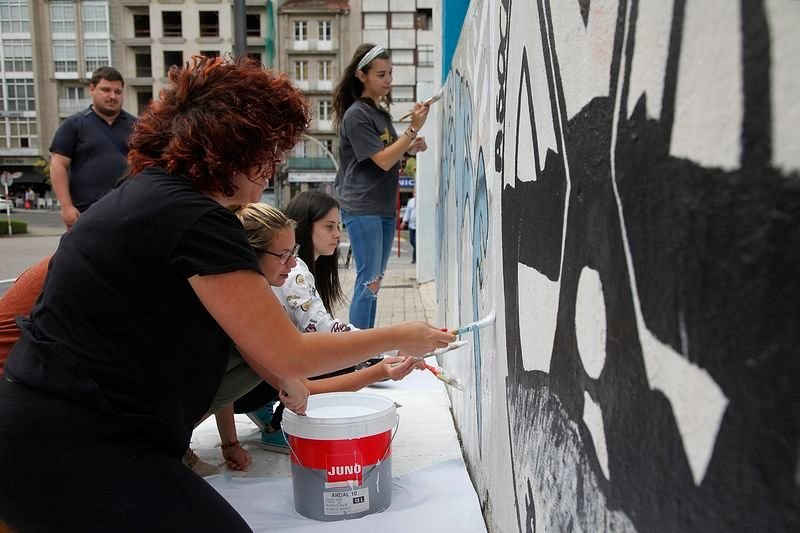 Voluntarios de Amencer participaron este lunes en la pintada del mural como inicio de la 32ª edición del Campamento Urbano (MIGUEL ÁNGEL).