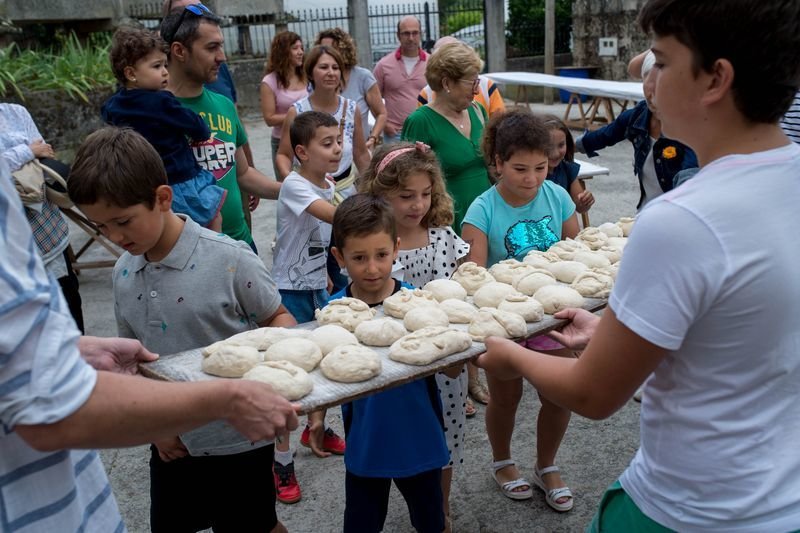 Menores junto con sus familiares obsersando el pan justo en el momento de ser metido en el horno (ÓSCAR PINAL).