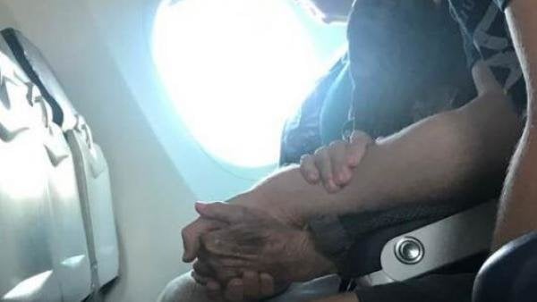 El joven agarra de la mano a la mujer, que está sufriendo durante el vuelo.