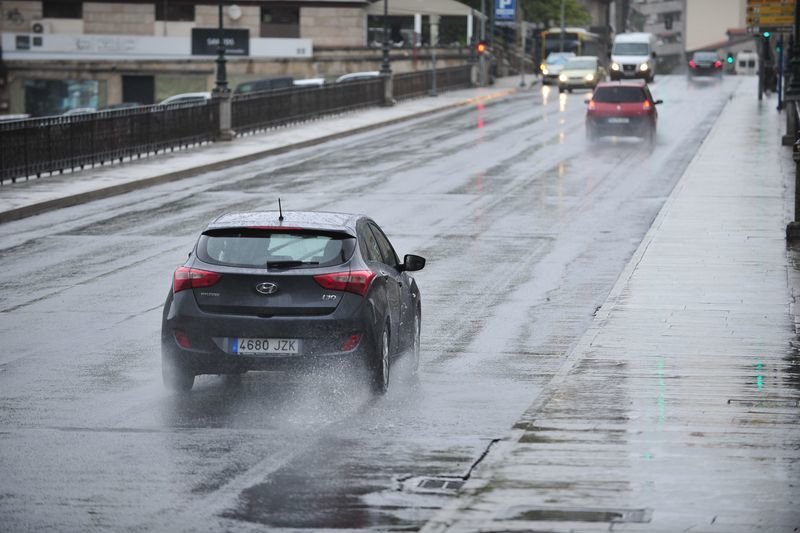 Un coche, circulando ayer por la mañana bajo una intensa lluvia en la rúa Progreso (JOSÉ PAZ).