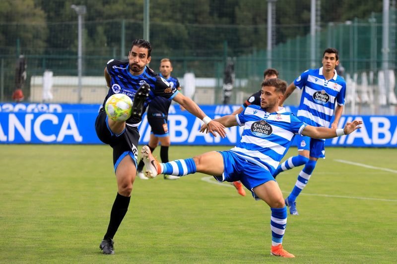 El central del Ourense CF Portela despeja la pelota con contundencia ante un jugador del Fabril.