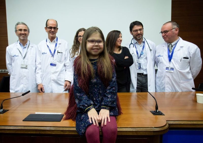 Iria, la niña trasplantada, con su madre y el equipo médico que la trató en el hospital catalán.