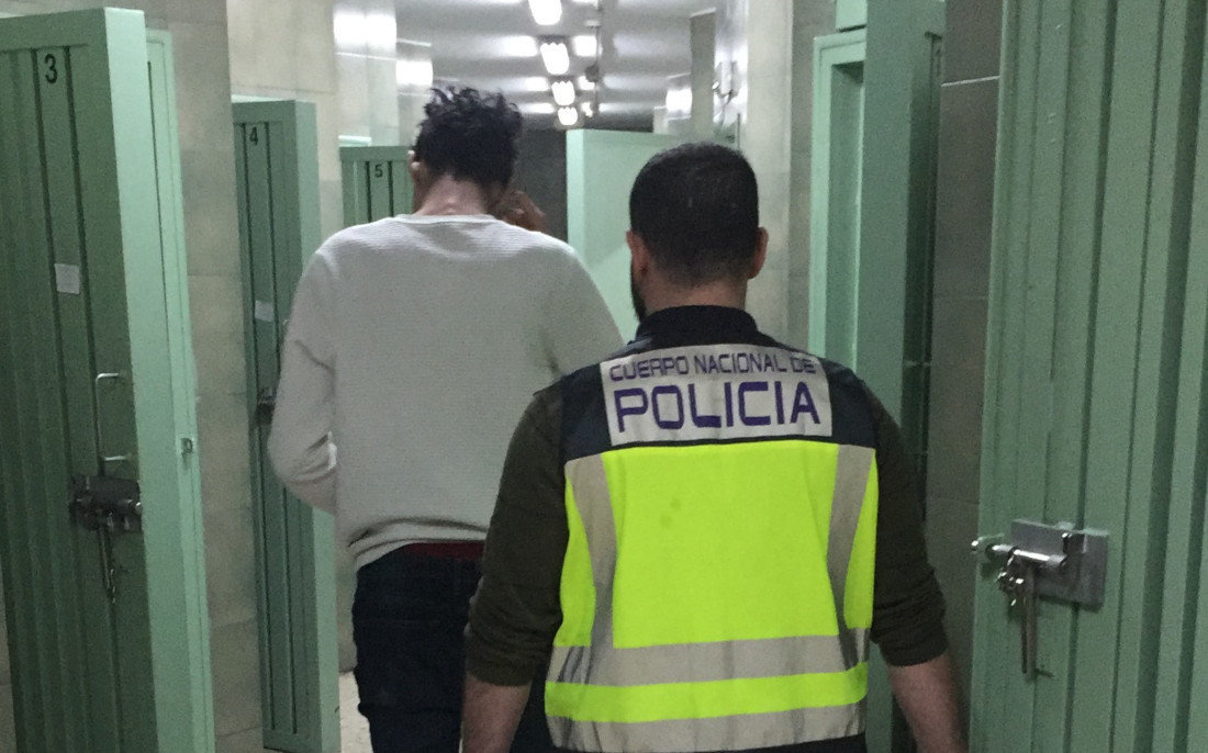 Un agente acompaña al hombre detenido por las dependencias policiales.