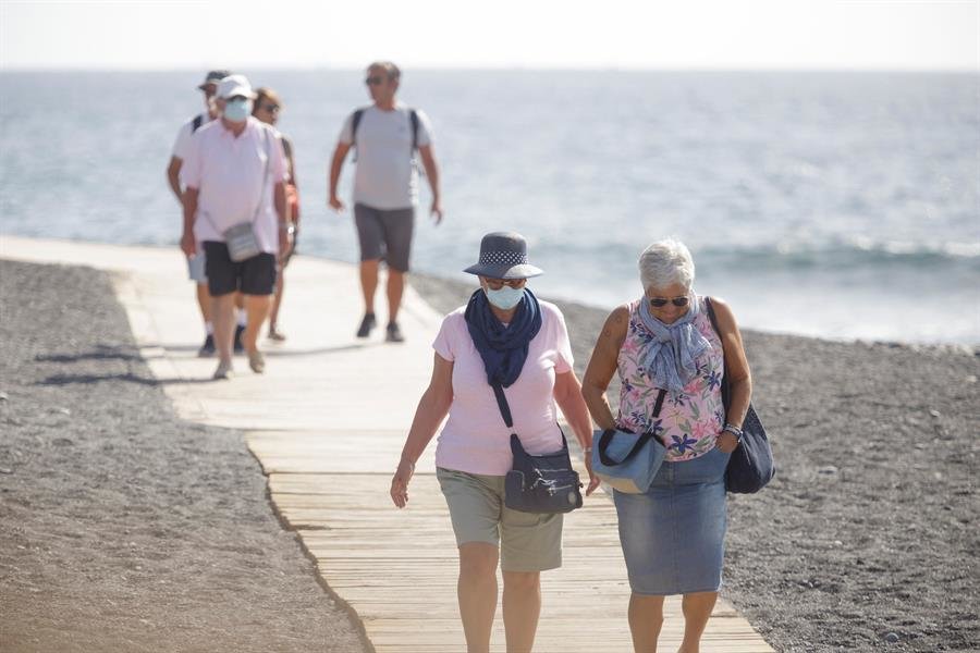 Personas caminando por una playa de Canarias con mascarillas (EFE).